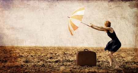 Redhead girl with umbrella at windy field.の写真素材