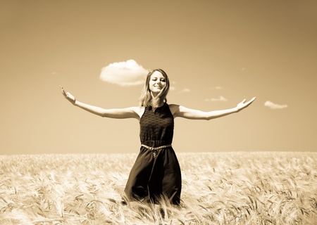 Girl at summer wheat field. Photo in old yellow color image style.の写真素材