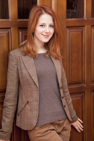 Young red-head girl near wooden doors.の写真素材