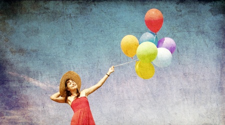 Brunette girl with colour balloons at blue sky background. Photo in old image style.の写真素材