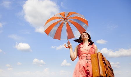 Brunette enchantress with umbrella and suitcase の写真素材