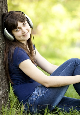 Young fashion girl with headphones at green spring grass.の写真素材
