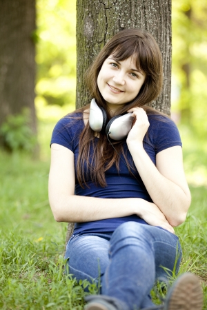 Young fashion girl with headphones at green spring grass.の写真素材