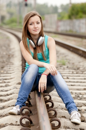 Teen girl with headphones at railways.の写真素材