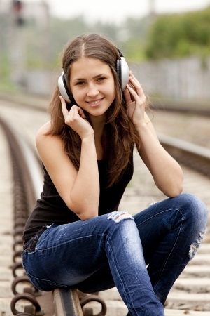 Teen girl with headphones at railways.の写真素材