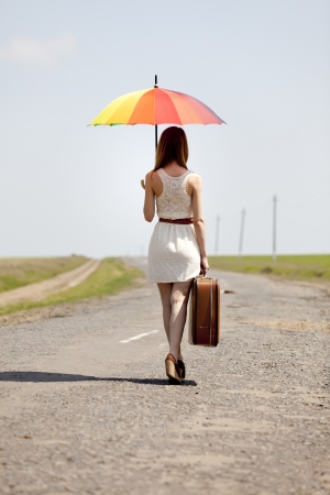 Young fashion girl with umbrella and suitcase at spring outdoor.の写真素材