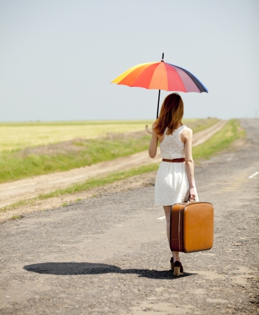 Young fashion girl with umbrella and suitcase at spring outdoor.の写真素材