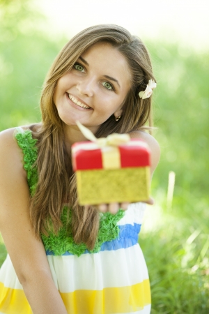 Beautiful teen girl with gift in the park at green grass.の写真素材