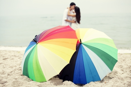 Couple kissing at the beach and umbrellaの写真素材