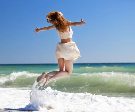 Young redhead girl jumping at the beach.の写真素材