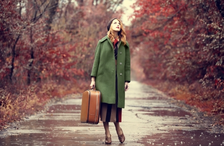 Style redhead girl with suitcase at beautiful autumn alley.