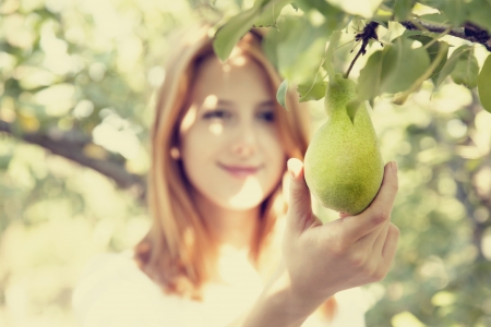 Redhead girl holding pear in gardenの写真素材