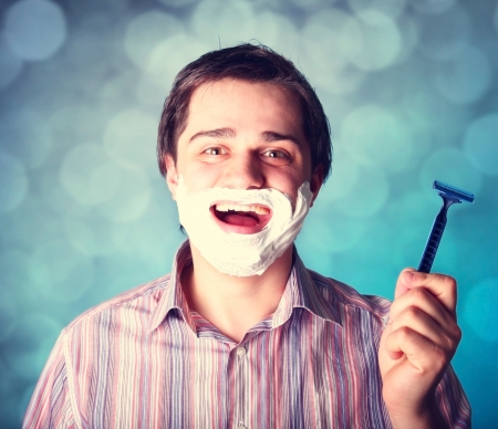 Man shaving isolated on blue backgroundの写真素材