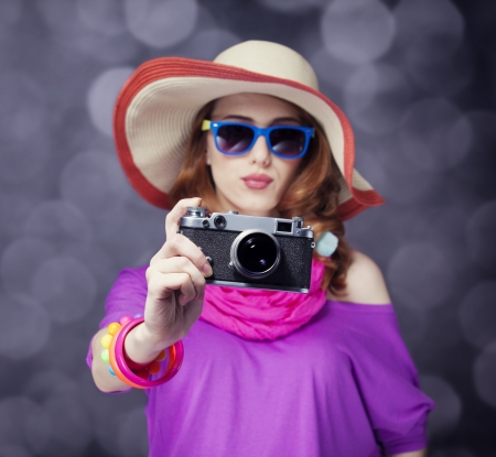 Funny redhead girl in hat with camera and bokeh at backgroundの写真素材