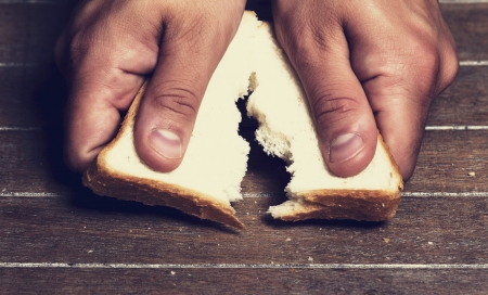 hand breaking apart a bread loaf against