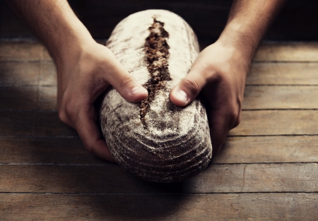 Baker's hands with a bread. Photo with high contrast