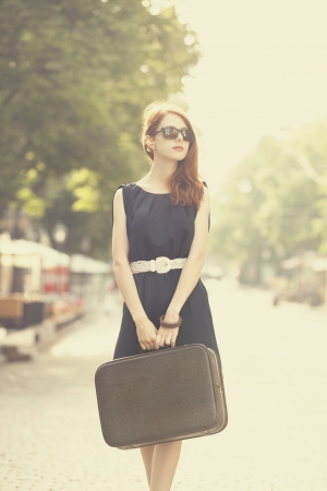 Young woman with suitcase on the city streetの写真素材