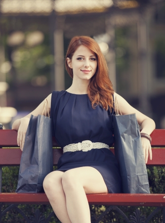 Style redhead women sitting on the bench with shopping bagsの写真素材