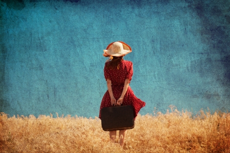 Redhead girl with suitcase at summer field.の写真素材