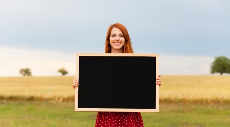 Redhead girl with blackboard at wheat fieldの写真素材