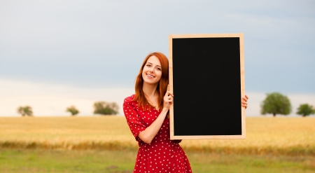 Redhead girl with blackboard at wheat fieldの写真素材