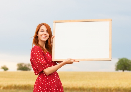 Redhead girl with blackboard at wheat fieldの写真素材