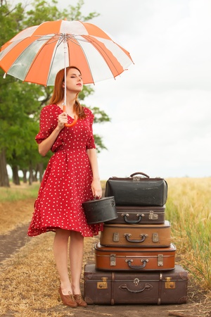 Redhead girl with suitcases at outdoorの写真素材