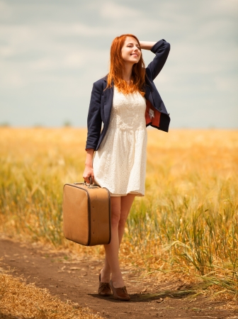 Redhead girl with suitcase at outdoor.の写真素材