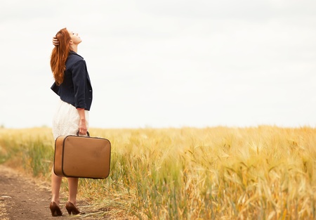 Redhead girl with suitcase at outdoor.の写真素材