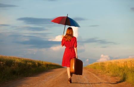 Redhead girl with umbrella and suitcase at outdoorの写真素材