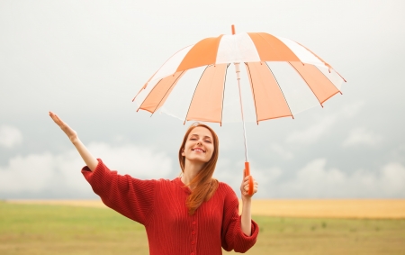 Redhead girl with umbrella at meadowの写真素材