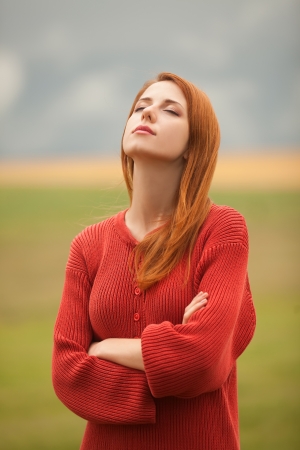 Redhead girl at meadow near wheat fieldの写真素材