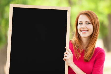 Redhead girl with blackboard at outdoorの写真素材