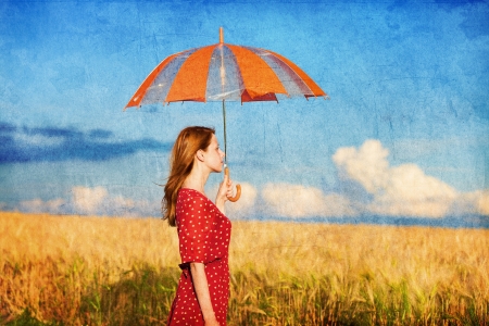 Redhead girl with umbrella at fieldの写真素材