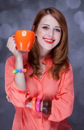 Redhead girl with cup. Studio shot.の写真素材