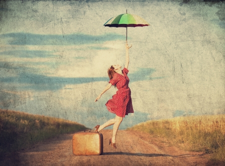 Redhead girl with umbrella and suitcase at outdoorの写真素材