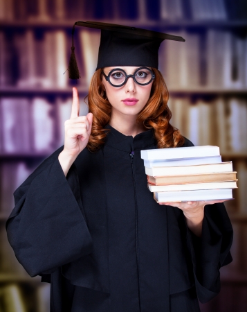 graduating student girl in an academic gown with booksの写真素材
