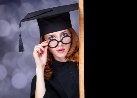 graduating student girl in an academic gown near blackboardの写真素材