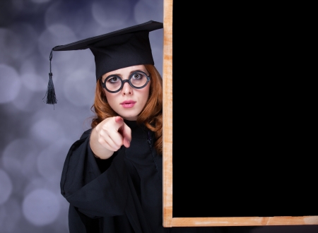 graduating student girl in an academic gown near blackboardの写真素材