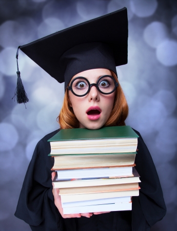 graduating student girl in an academic gown with booksの写真素材