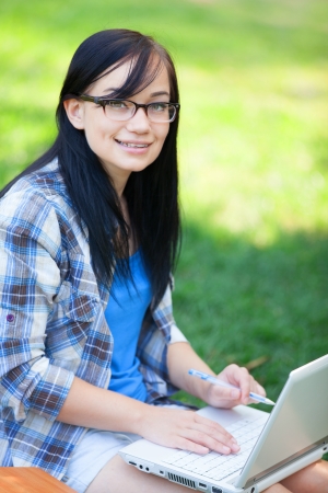 Teen girl with laptop in the park.の写真素材
