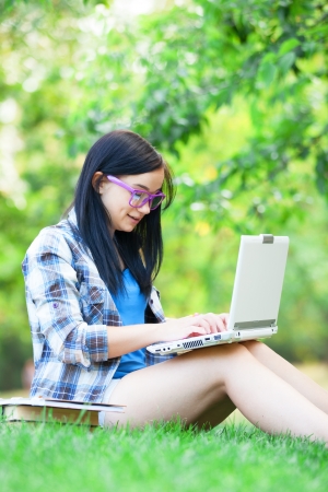 Teen girl with laptop in the park.の写真素材