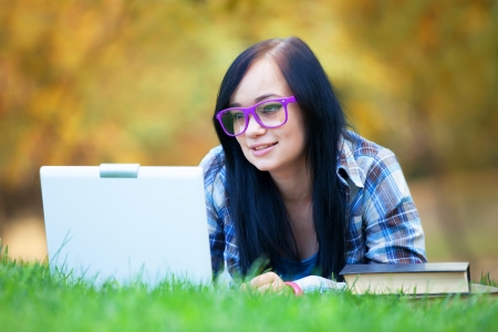 Teen girl with laptop in the park.の写真素材