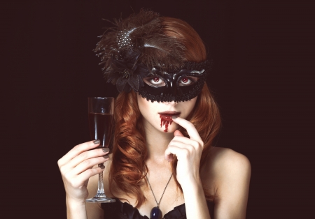Redhead vampire woman in mask with glass of blood. Photo in vintage style.の写真素材
