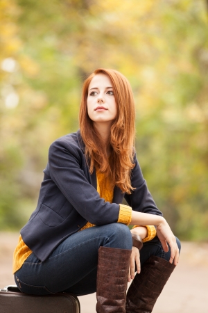 Girl with suitcase at autumn outdoorの写真素材