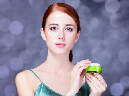 Beauty face of young redhead women with cosmetic cream on a cheek. の写真素材