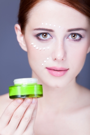 Beauty face of young redhead women with cosmetic cream on a cheek. の写真素材