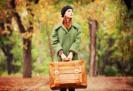 Redhead girl with suitcase at autumn outdoor.の写真素材