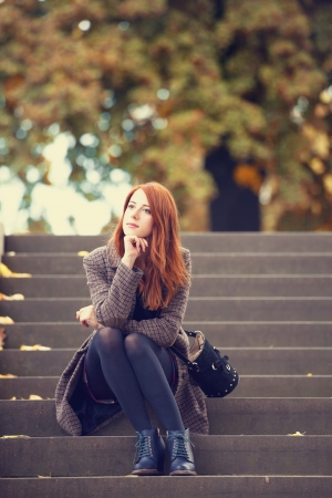 Redhead girl with sitting at outdoor.の写真素材