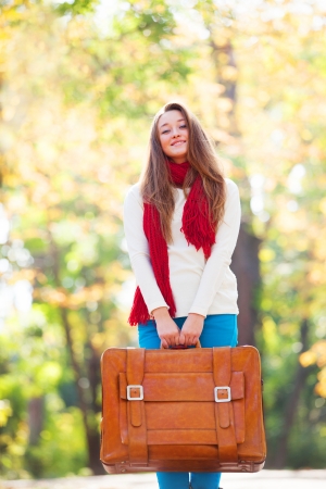 Teen girl with suitcase at autumn outdoorの写真素材
